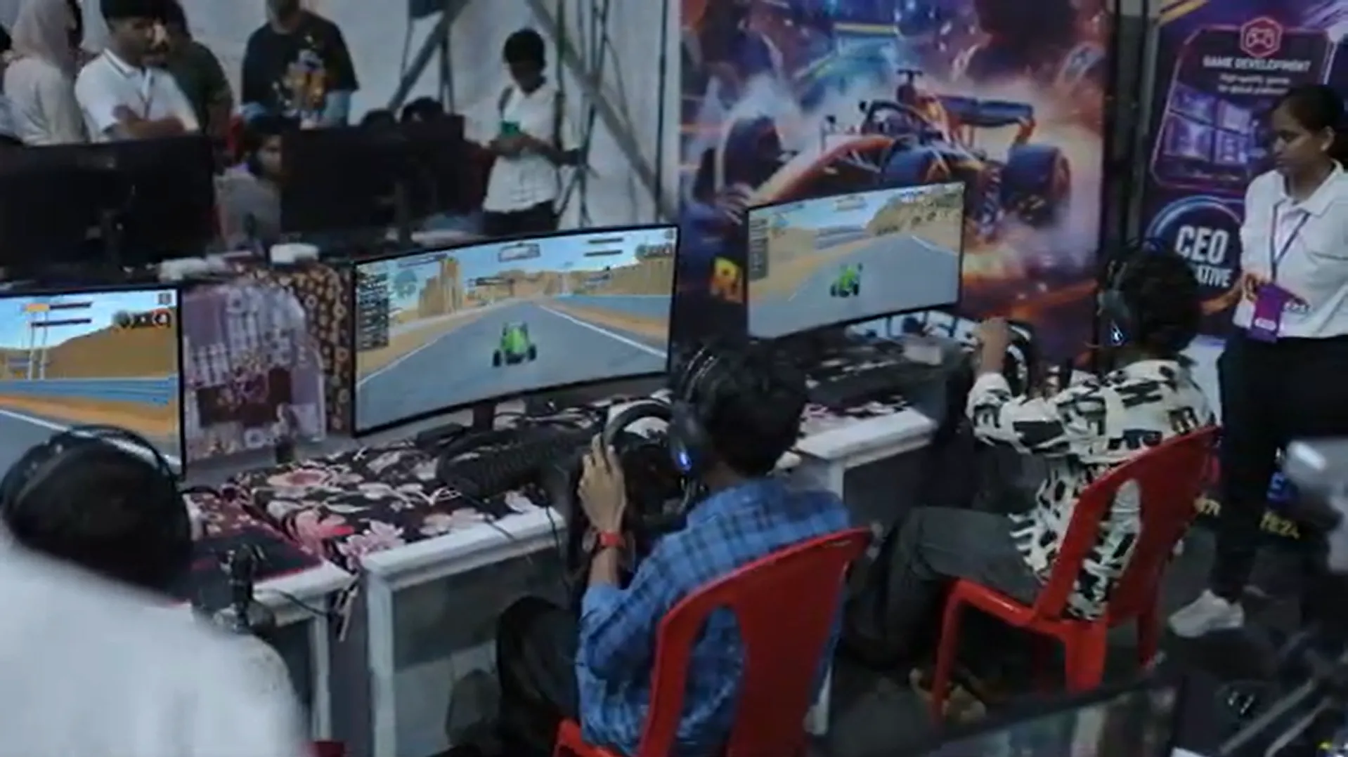 Boys playing multiplayer racing games at Revolution Games expo stall with crowd